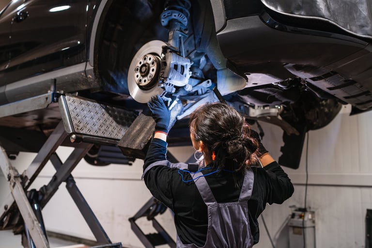 Female mechanic inspecting brakes on hydraulic lift