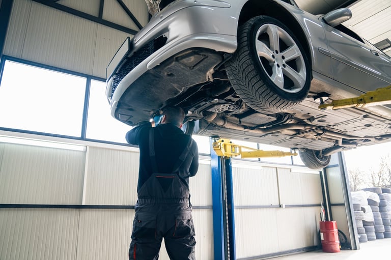 Serviceman checking car suspension on column lift
